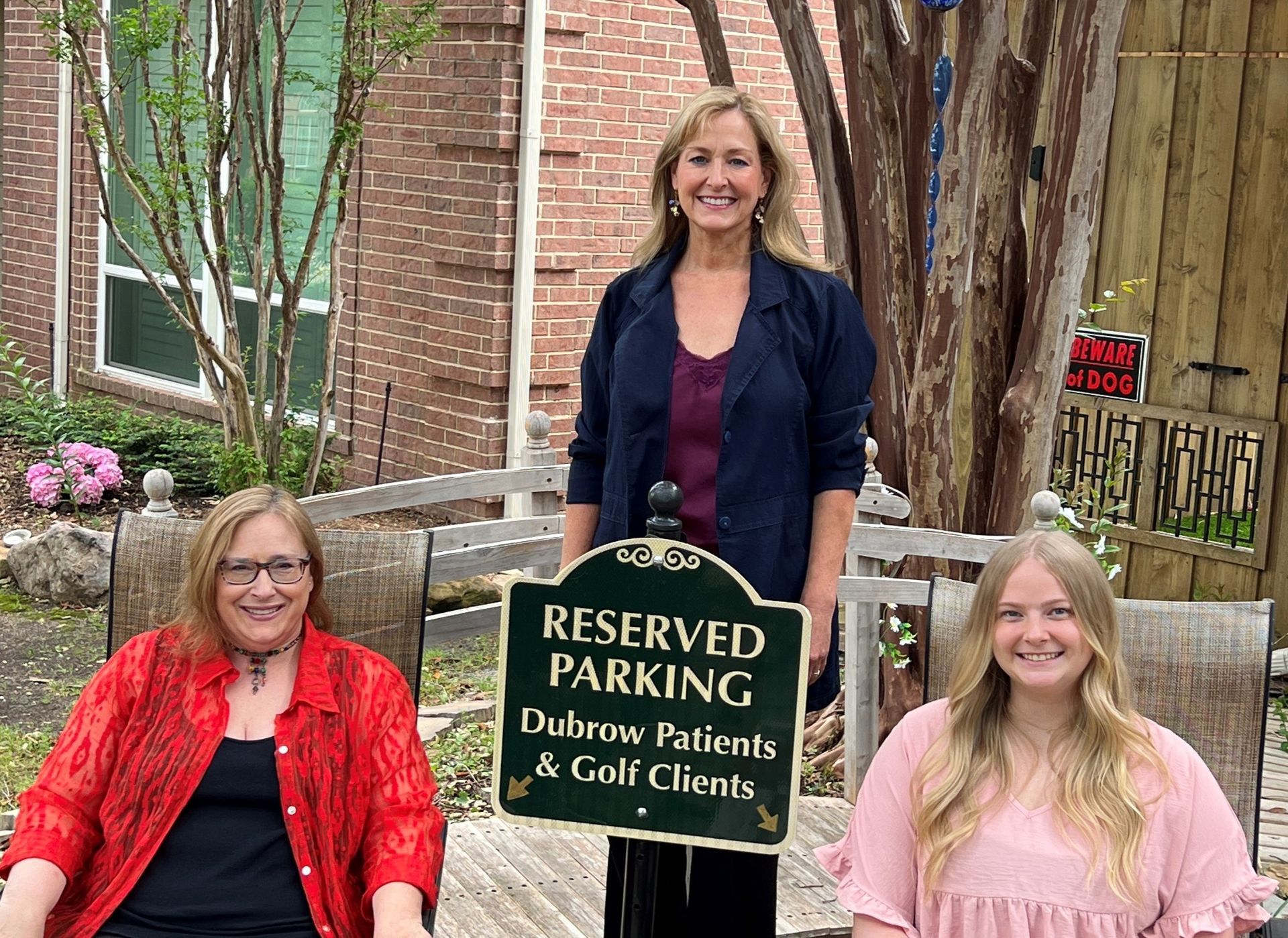 Three women are standing in front of a reserved parking sign.