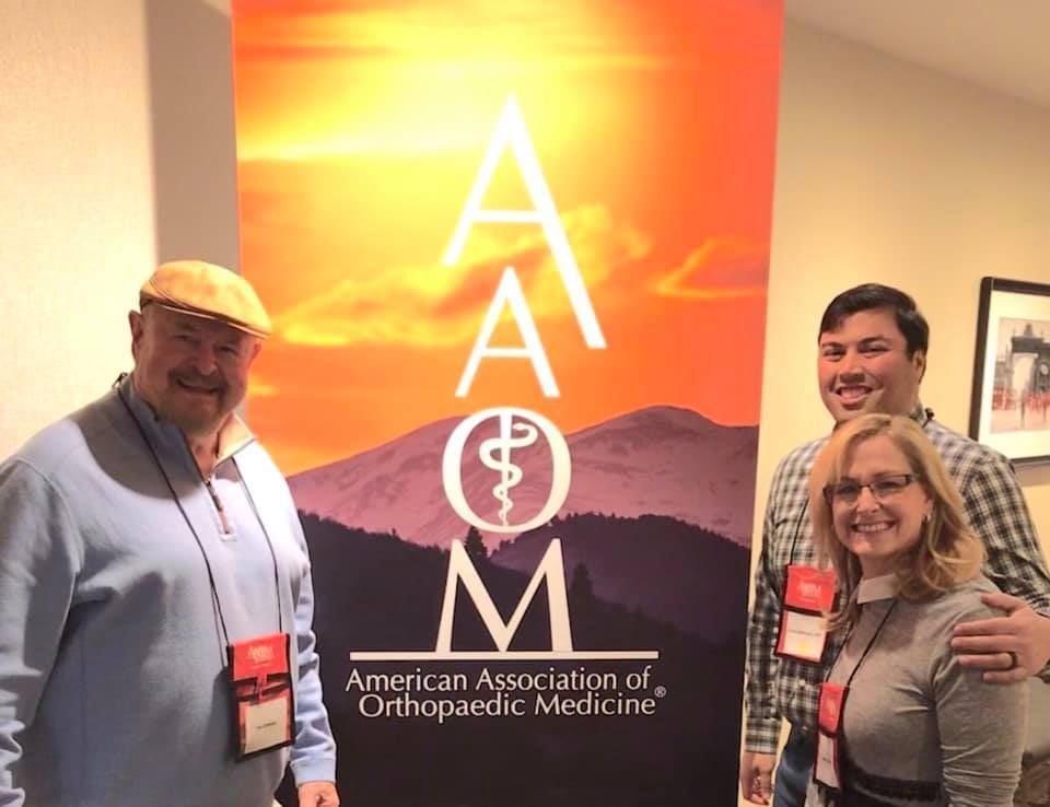 A group of people standing in front of an american association of orthopaedic medicine sign