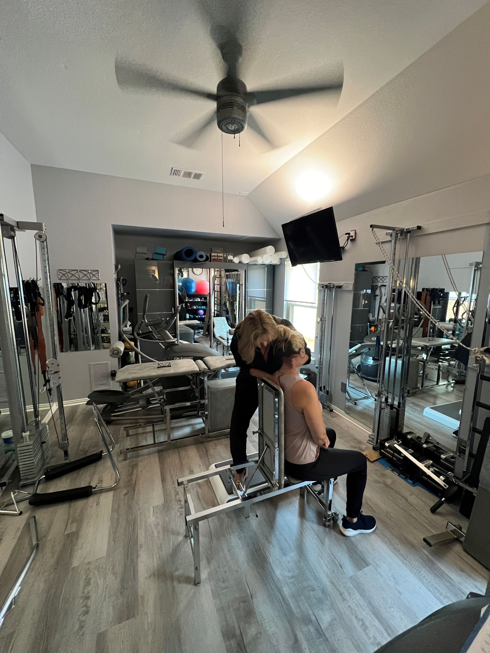 A man is standing next to a woman sitting on a bench in a gym.