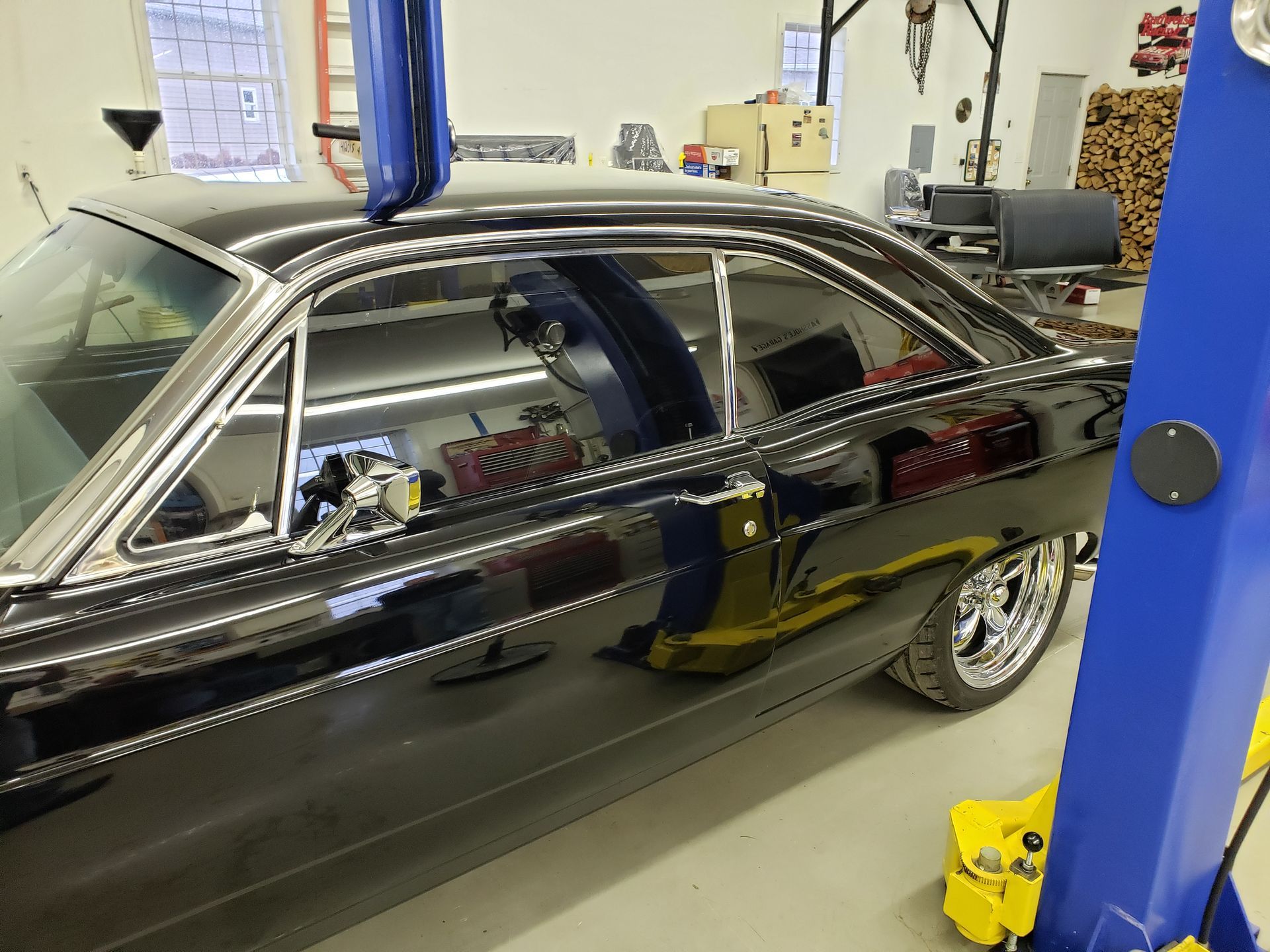 A black car is parked on a lift in a garage.