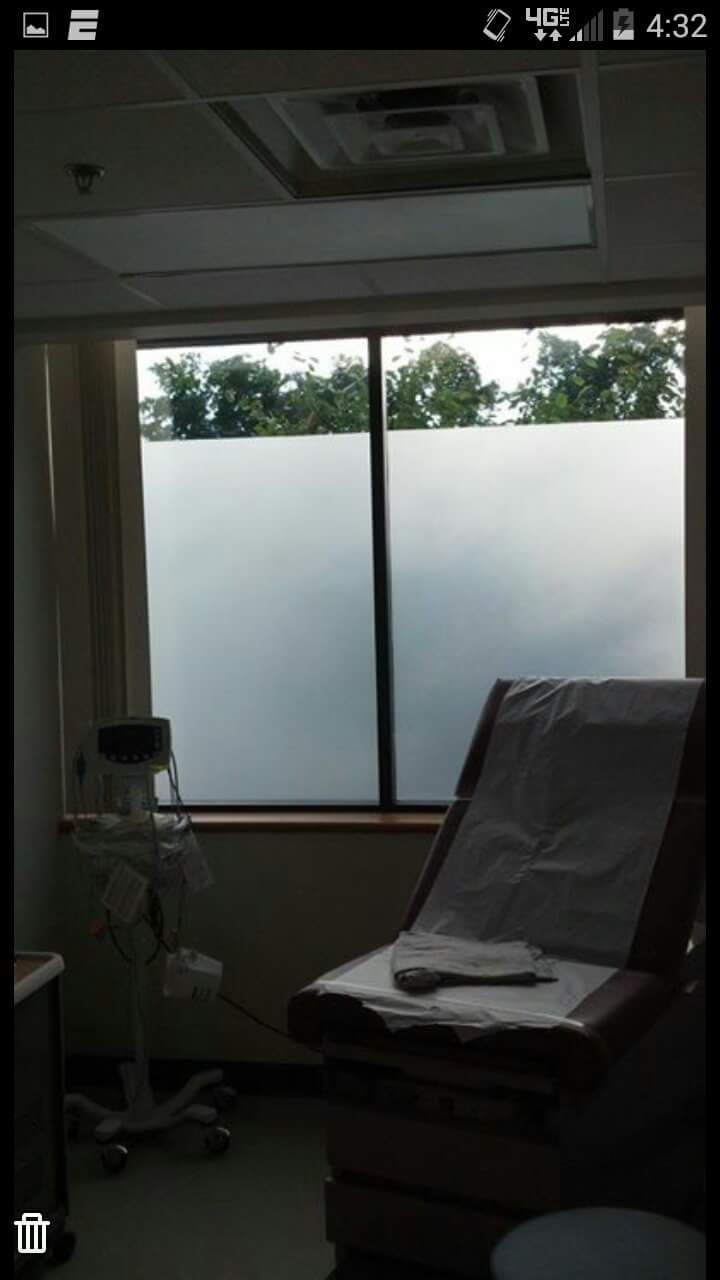A cell phone screen shows a hospital room with a chair and a window