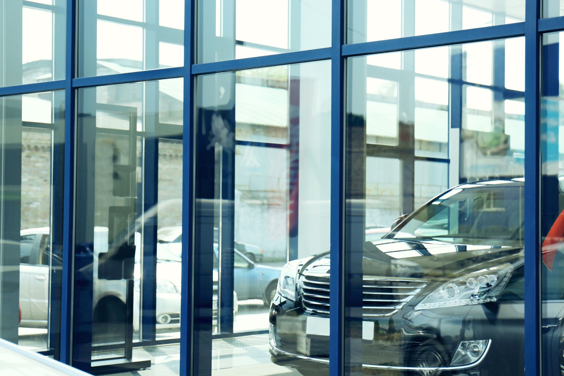 A car dealership with cars parked in front of a glass wall.