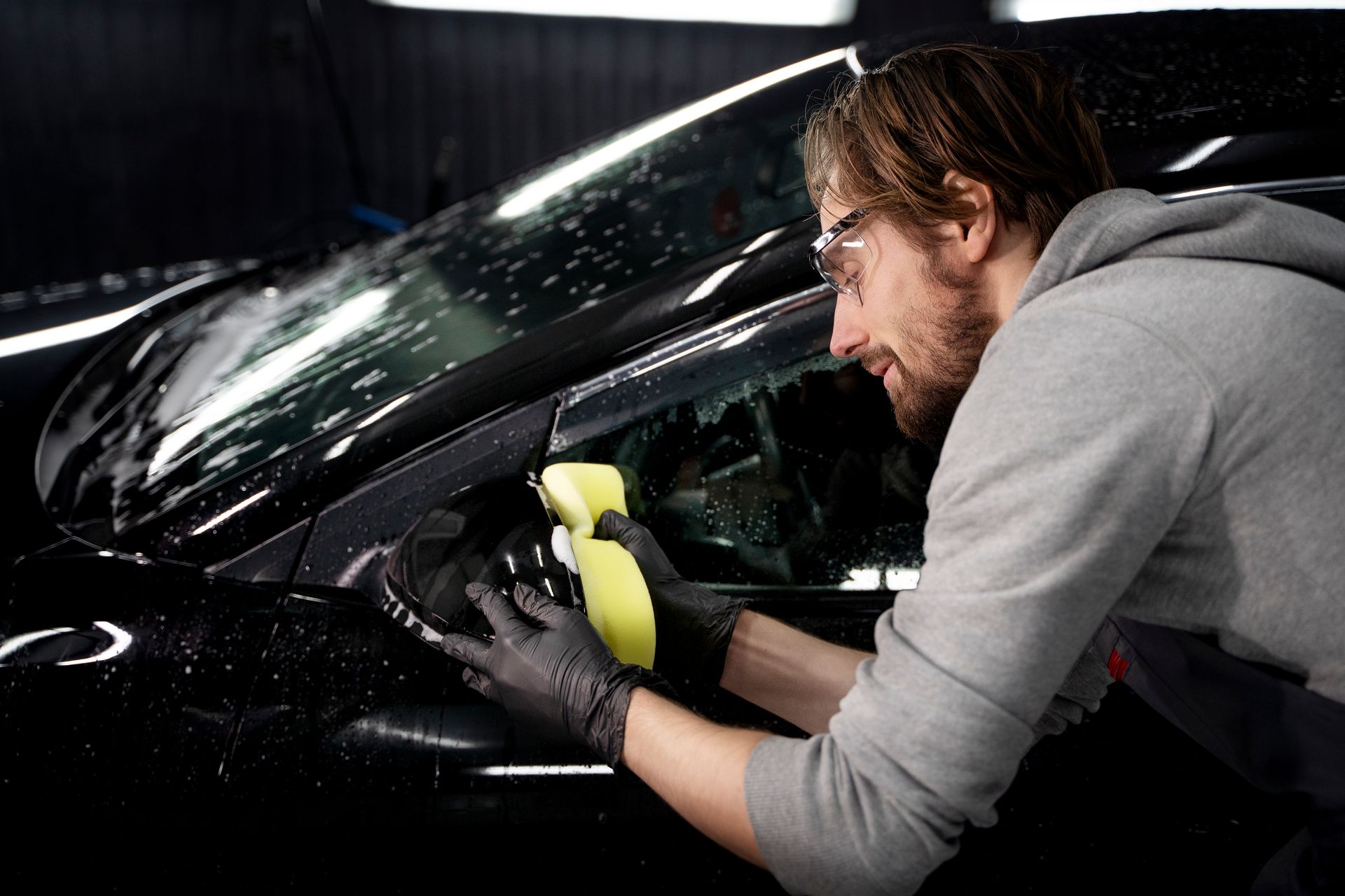 A man is polishing a car with a sponge.