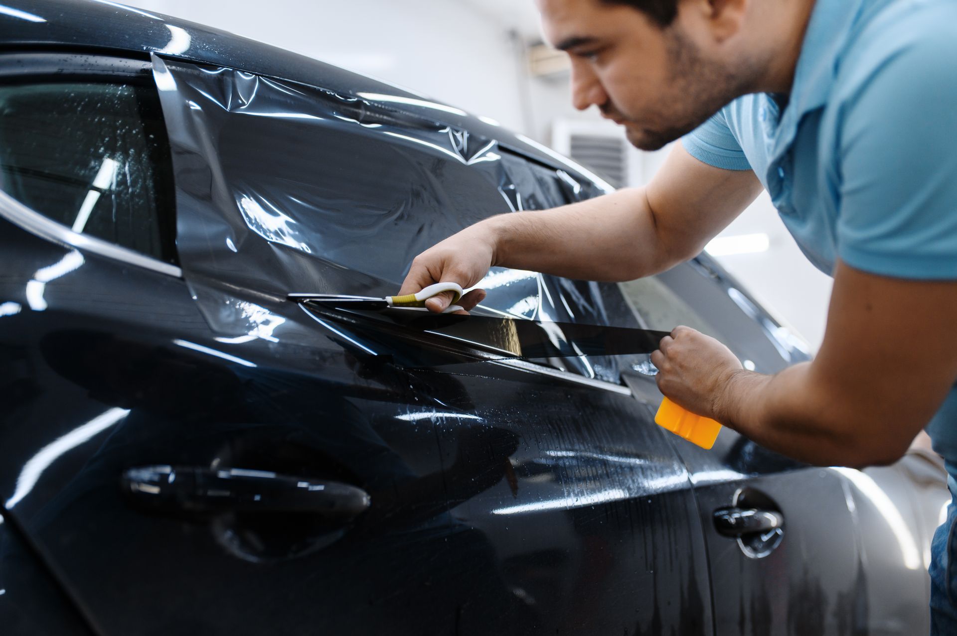 A man is applying tinted glass to a car window.