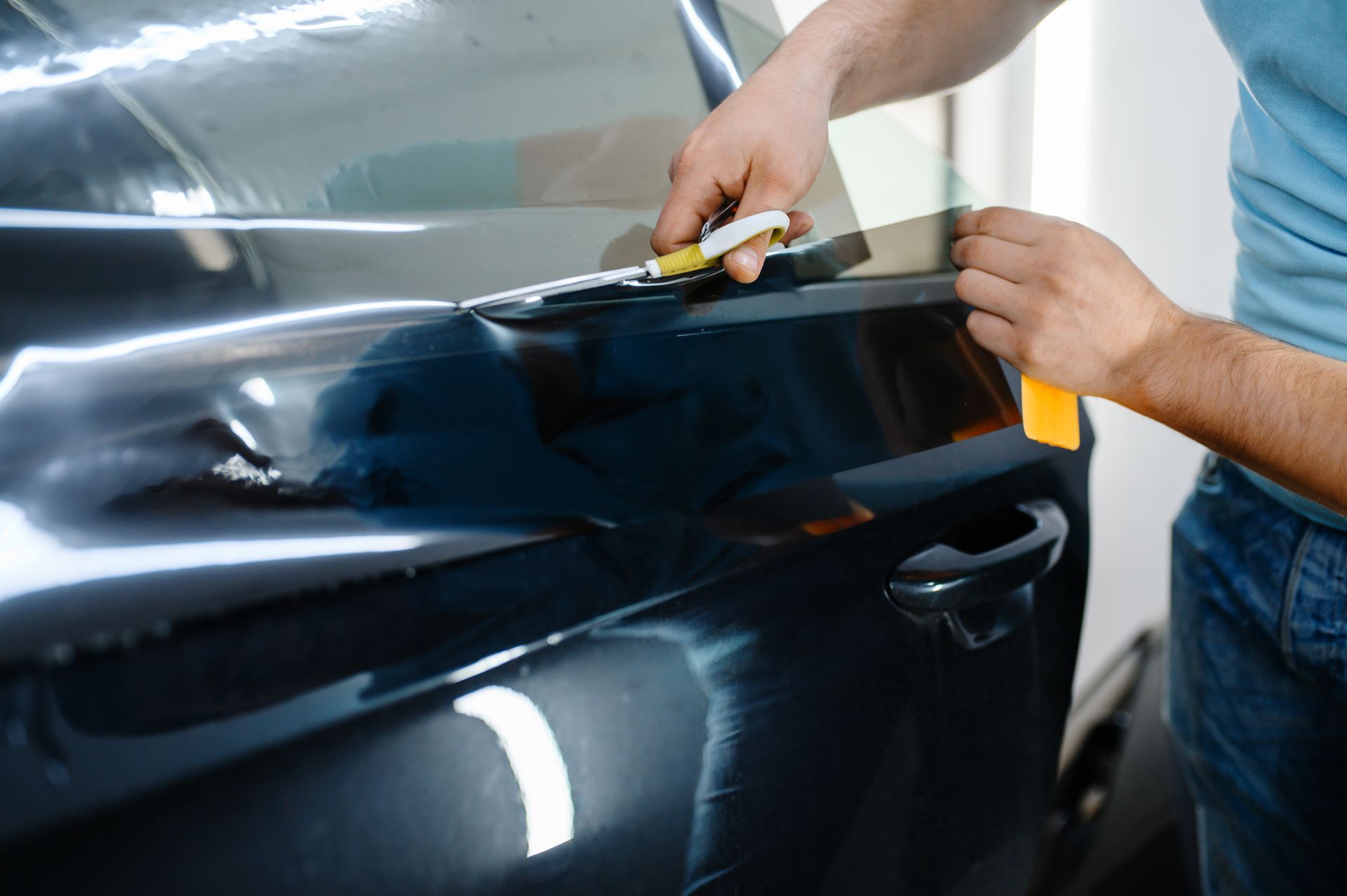 A man is applying tinted glass to a car window.