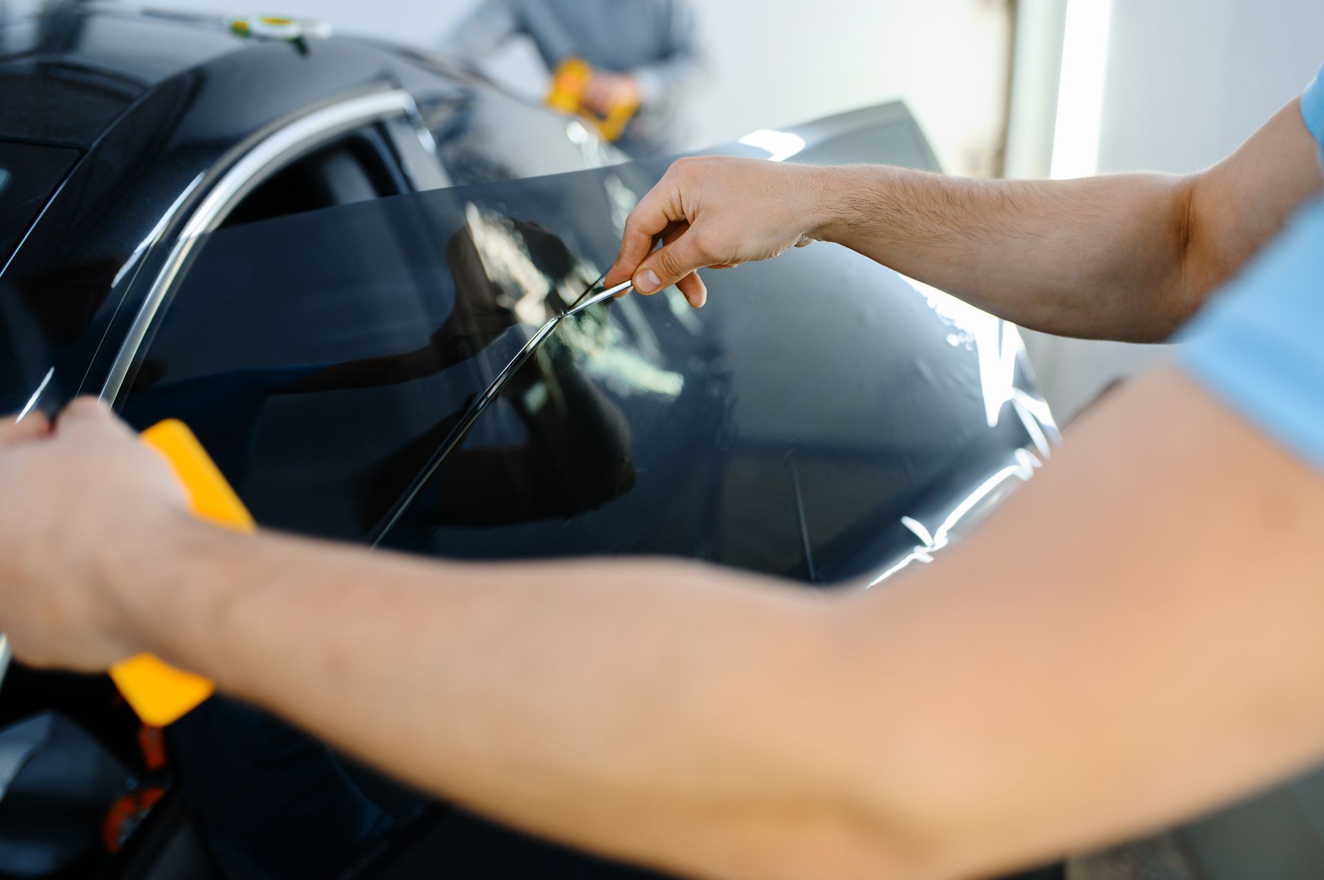A man is applying tinted glass to a car window.