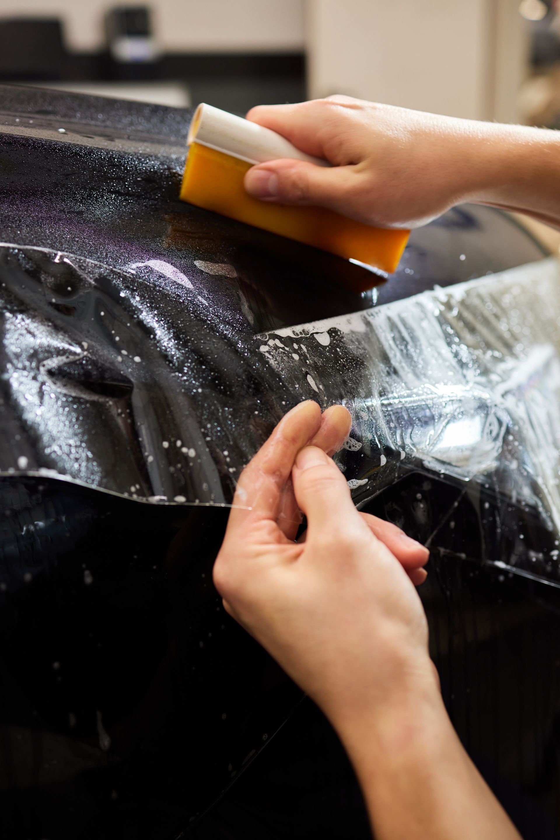 A person is applying a protective film to a car.
