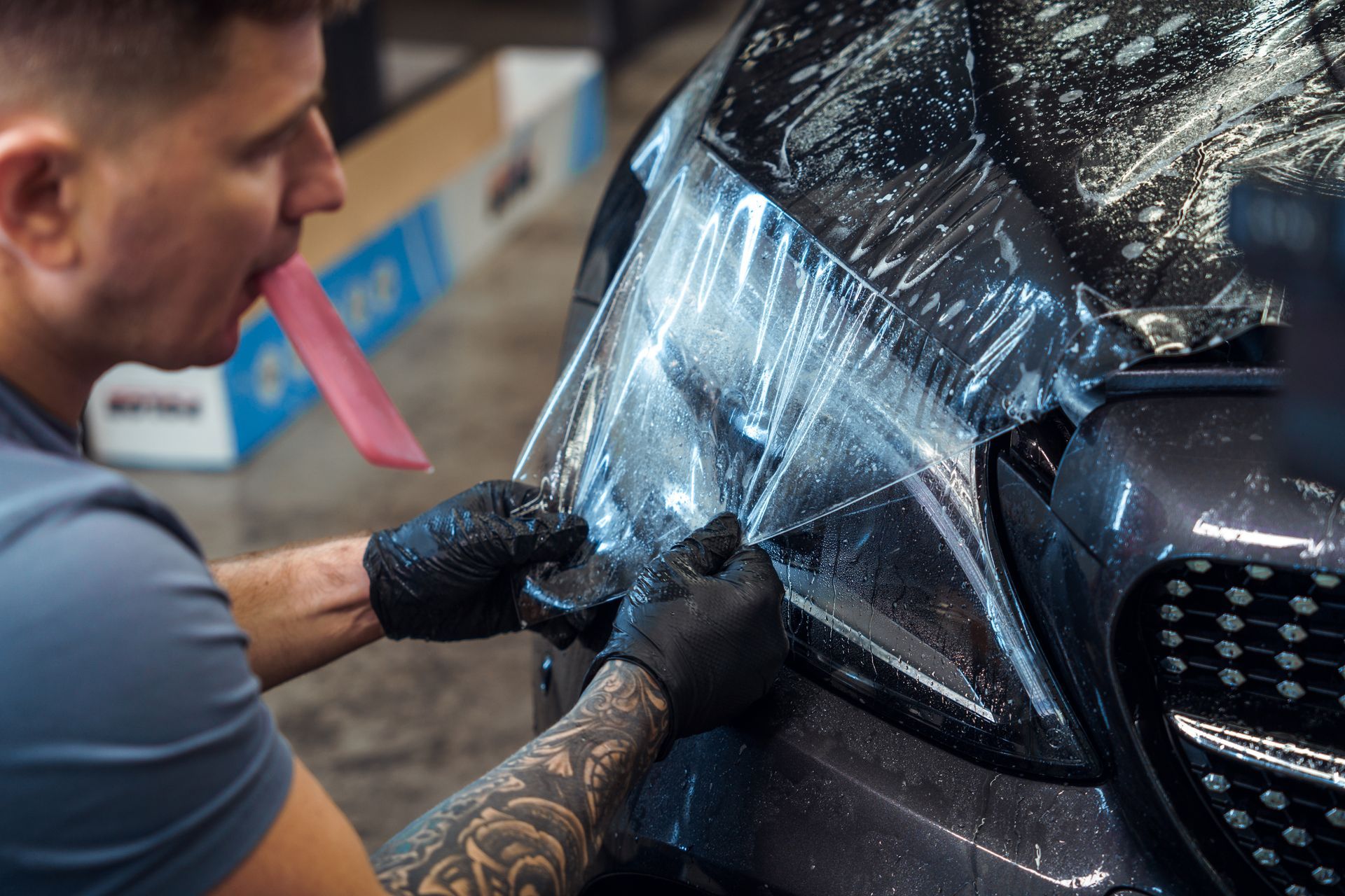 A man is wrapping a car with a plastic film.