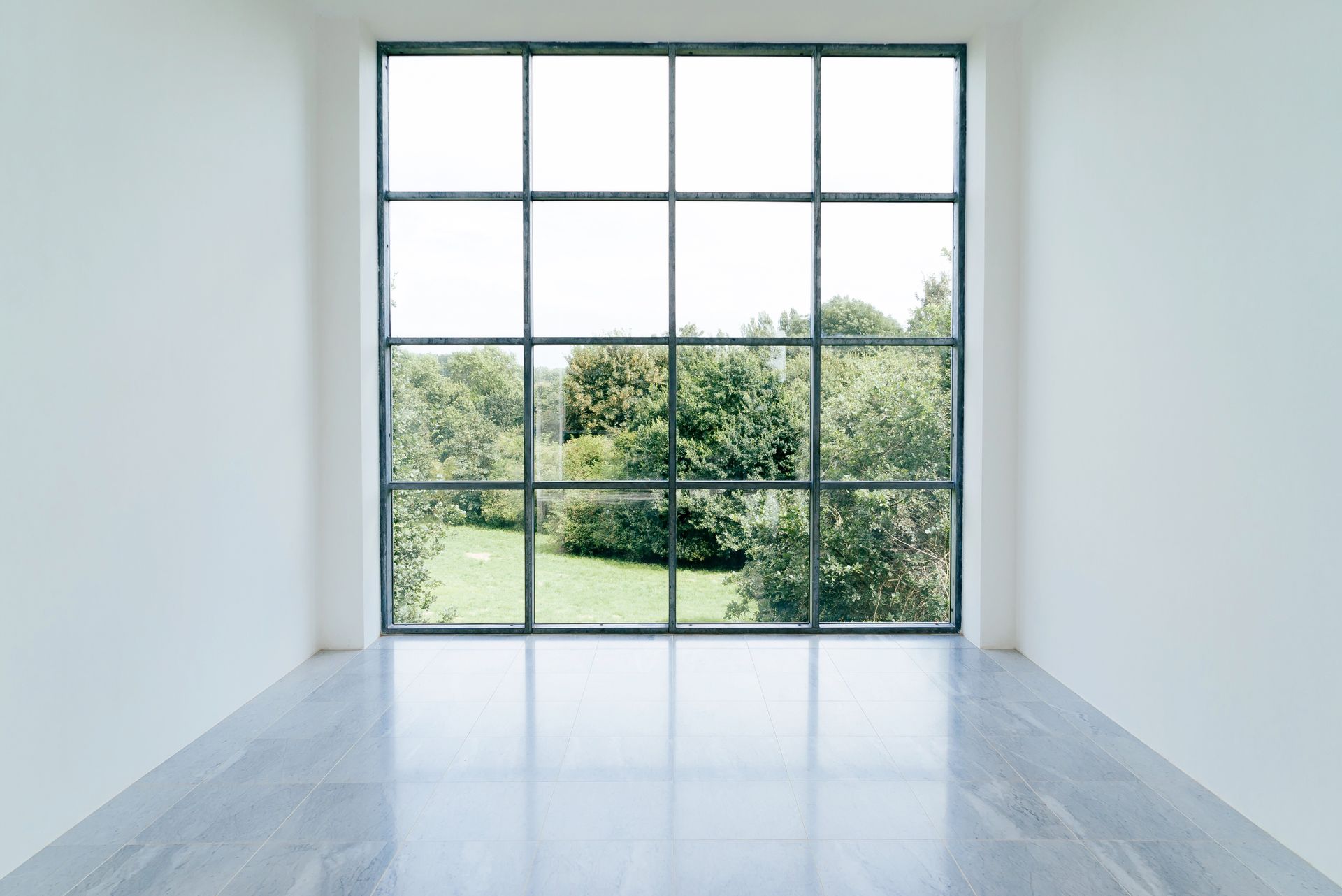 An empty room with a large window looking out to a park.