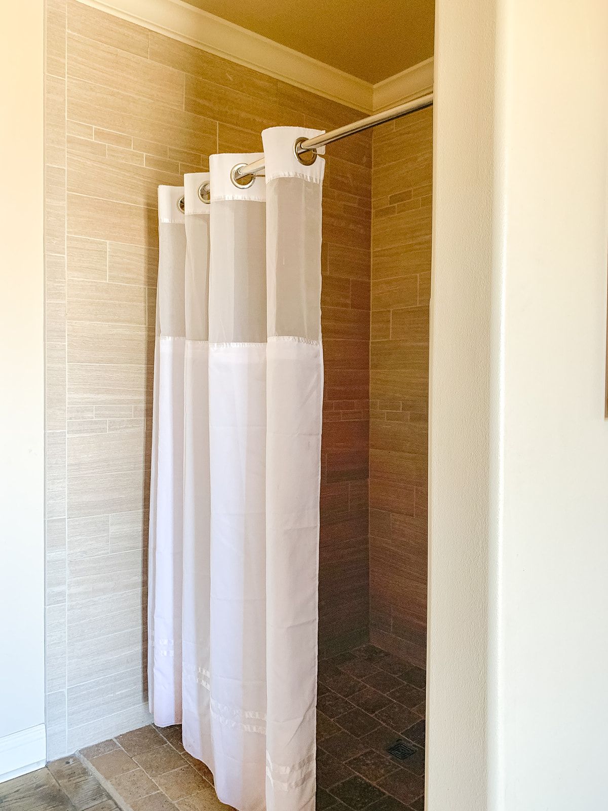 A white shower curtain is hanging in a bathroom.