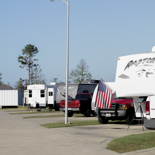 A red truck is parked next to a white rv that says raptor