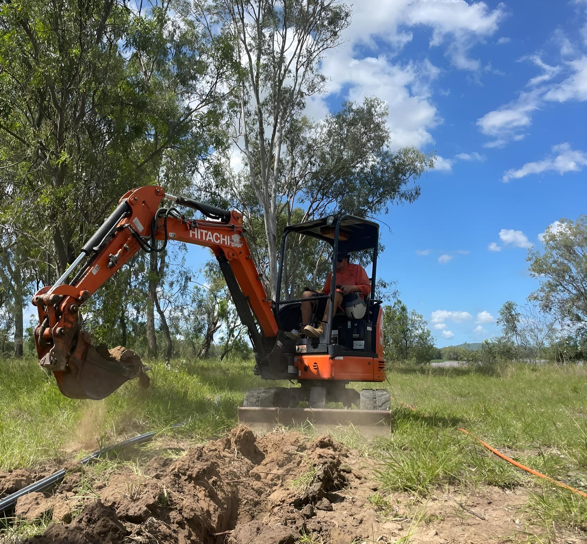 A Large Orange Excavator Is Digging a Hole in A Dirt Field — Jeff Thompson Excavator Hire Pty Ltd In Pink Lily, QLD