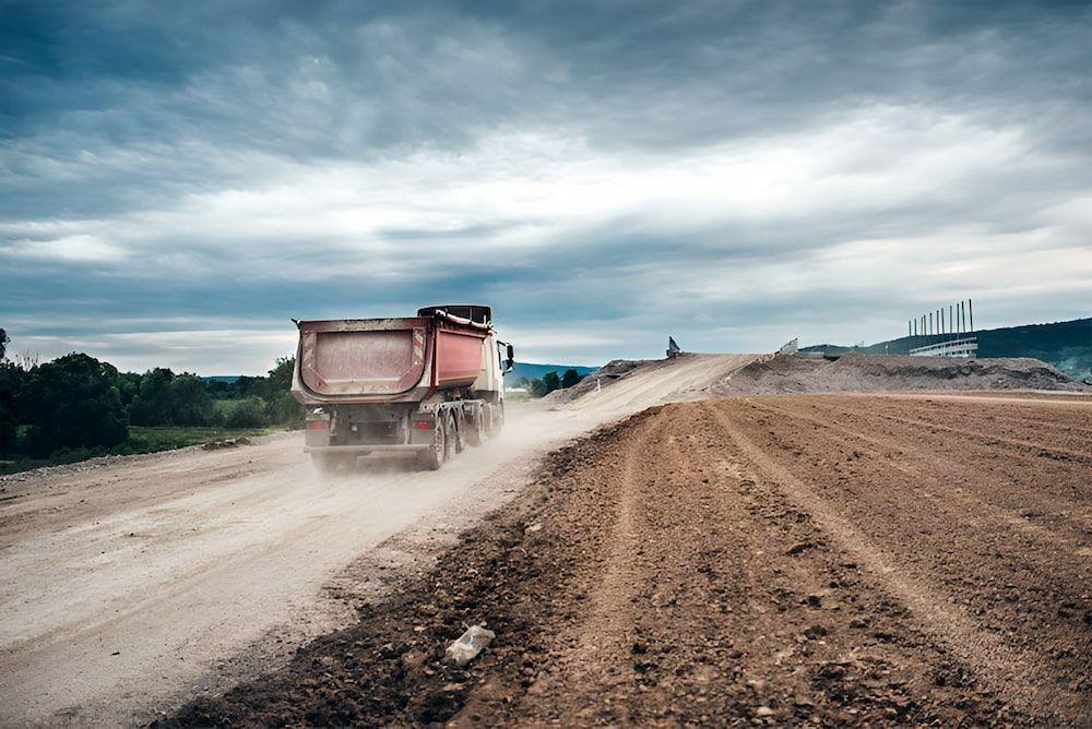 A Dump Truck Is Driving Down A Dirt Road — Jeff Thompson Excavator Hire Pty Ltd In Pink Lily, QLD