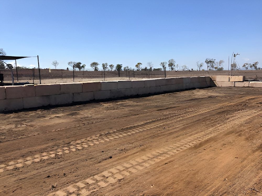 A Dirt Road With A Concrete Wall In The Background — Jeff Thompson Excavator Hire Pty Ltd In Pink Lily, QLD