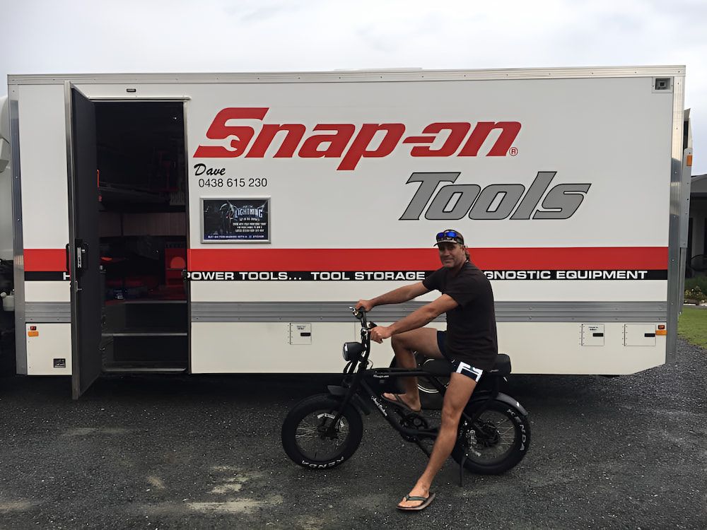A Man Is Riding A Bike In Front Of A Snap-on Tools Truck — Jeff Thompson Excavator Hire Pty Ltd In Pink Lily, QLD