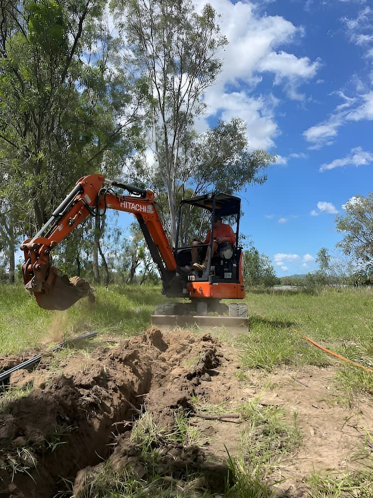 A Small Excavator Is Digging A Hole In A Field — Jeff Thompson Excavator Hire Pty Ltd In Pink Lily, QLD