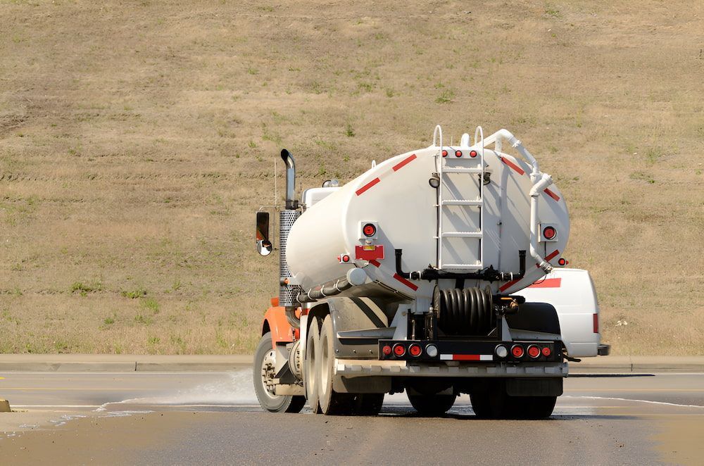 A White Tanker Truck Is Driving Down A Road — Jeff Thompson Excavator Hire Pty Ltd In Pink Lily, QLD