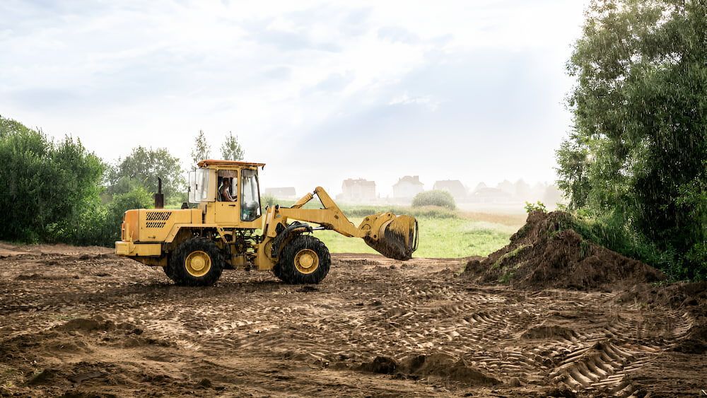 A Yellow Bulldozer Is Driving Through A Dirt Field — Jeff Thompson Excavator Hire Pty Ltd In Pink Lily, QLD