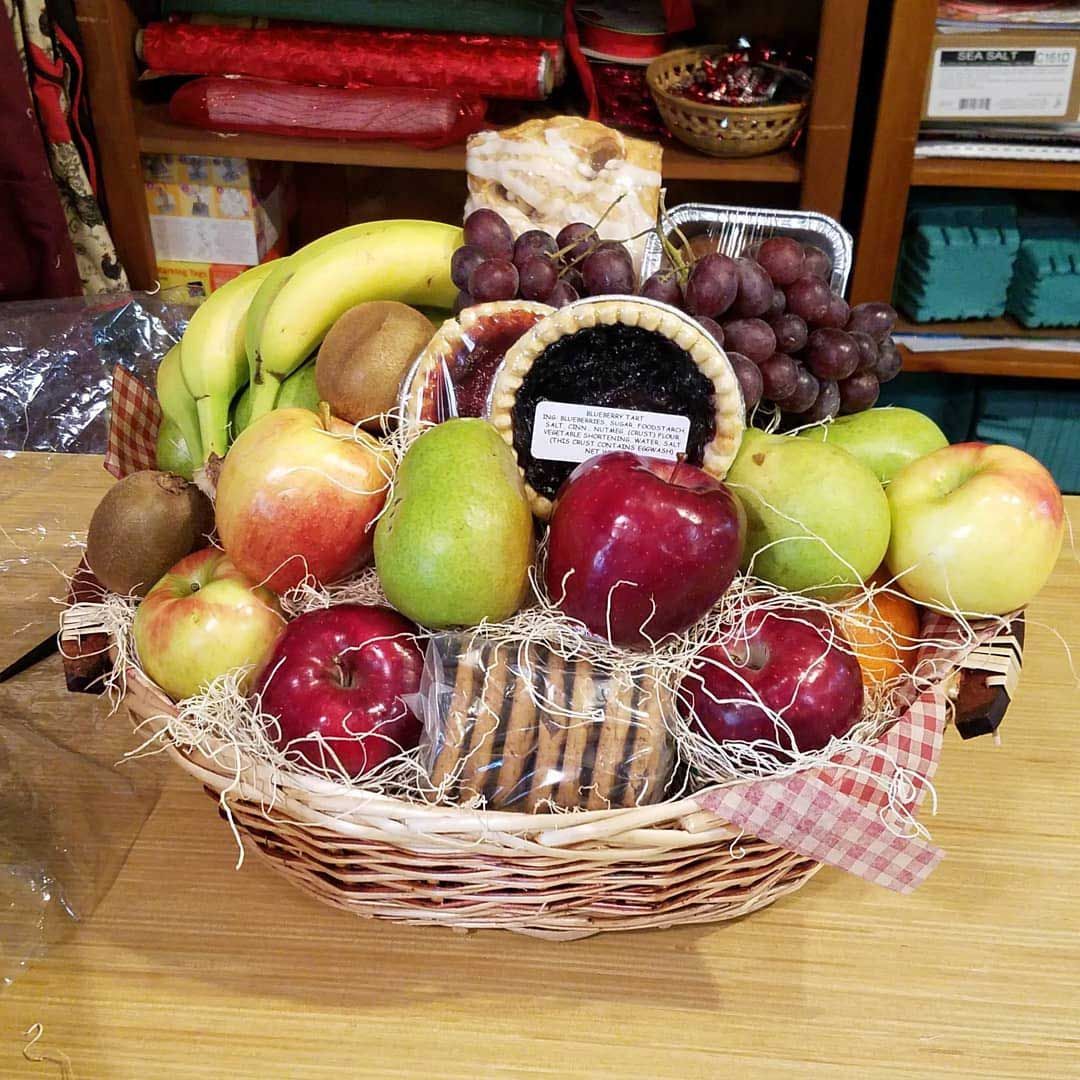 Fruit basket with apples, pears, grapes, bananas, kiwi, and pie.