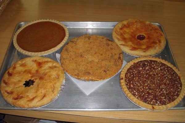Tray of five pies: pumpkin, crumble, pecan, and two others with cut-out designs.