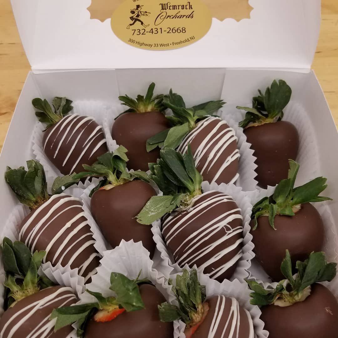 Box of chocolate-covered strawberries, some drizzled with white chocolate, in a white box.