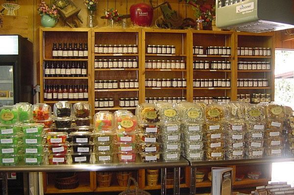 Shelves with jars of preserves and packaged candies for sale at a market.