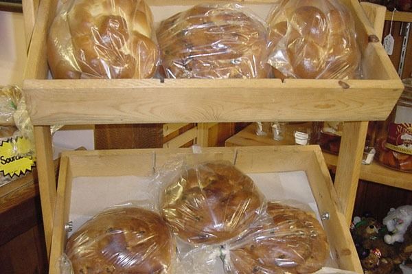 Wooden display stand holding loaves of bread wrapped in plastic.