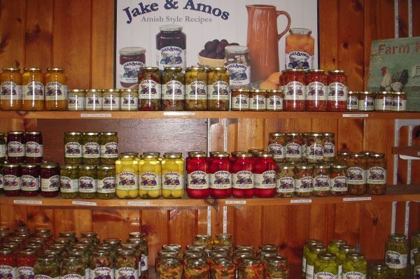 Shelves of Jake & Amos Amish-style jarred foods for sale, including pickles and jams.