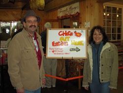 Man and woman pose beside a whiteboard sign: 