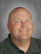 A bald man in a green shirt is smiling for the camera.