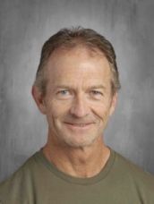 A man in a green shirt is smiling for the camera.