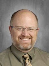 A man with a beard and glasses is smiling for the camera.