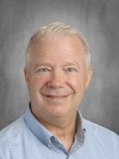 A man in a blue striped shirt is smiling for the camera.