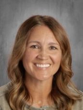 A woman with long brown hair is smiling for the camera.