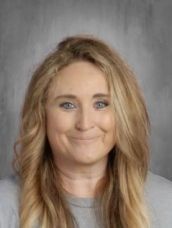 A woman with long blonde hair and blue eyes is smiling for a picture.