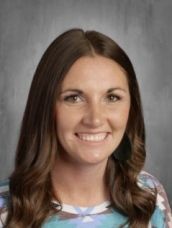A woman with long brown hair is smiling for a picture.