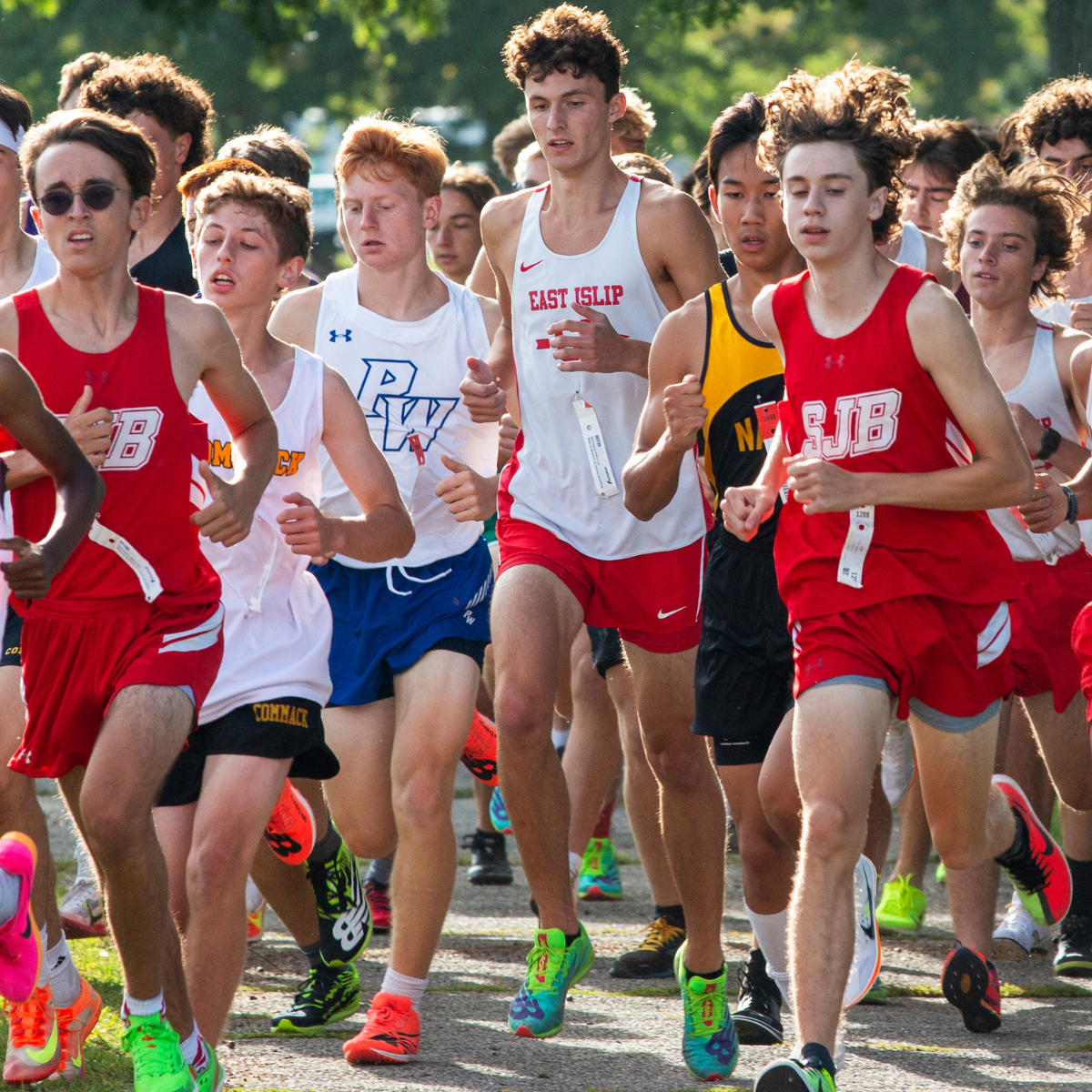 A group of young men are running in a race and one of them is wearing a red jersey that says rjb