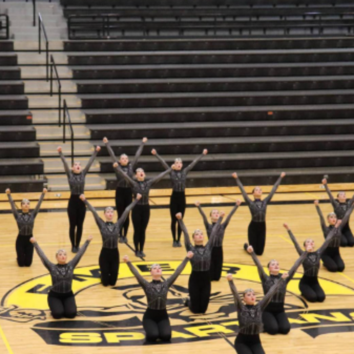 A group of people are kneeling on the floor with their arms in the air