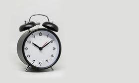 A black and white alarm clock with bells on a white background.