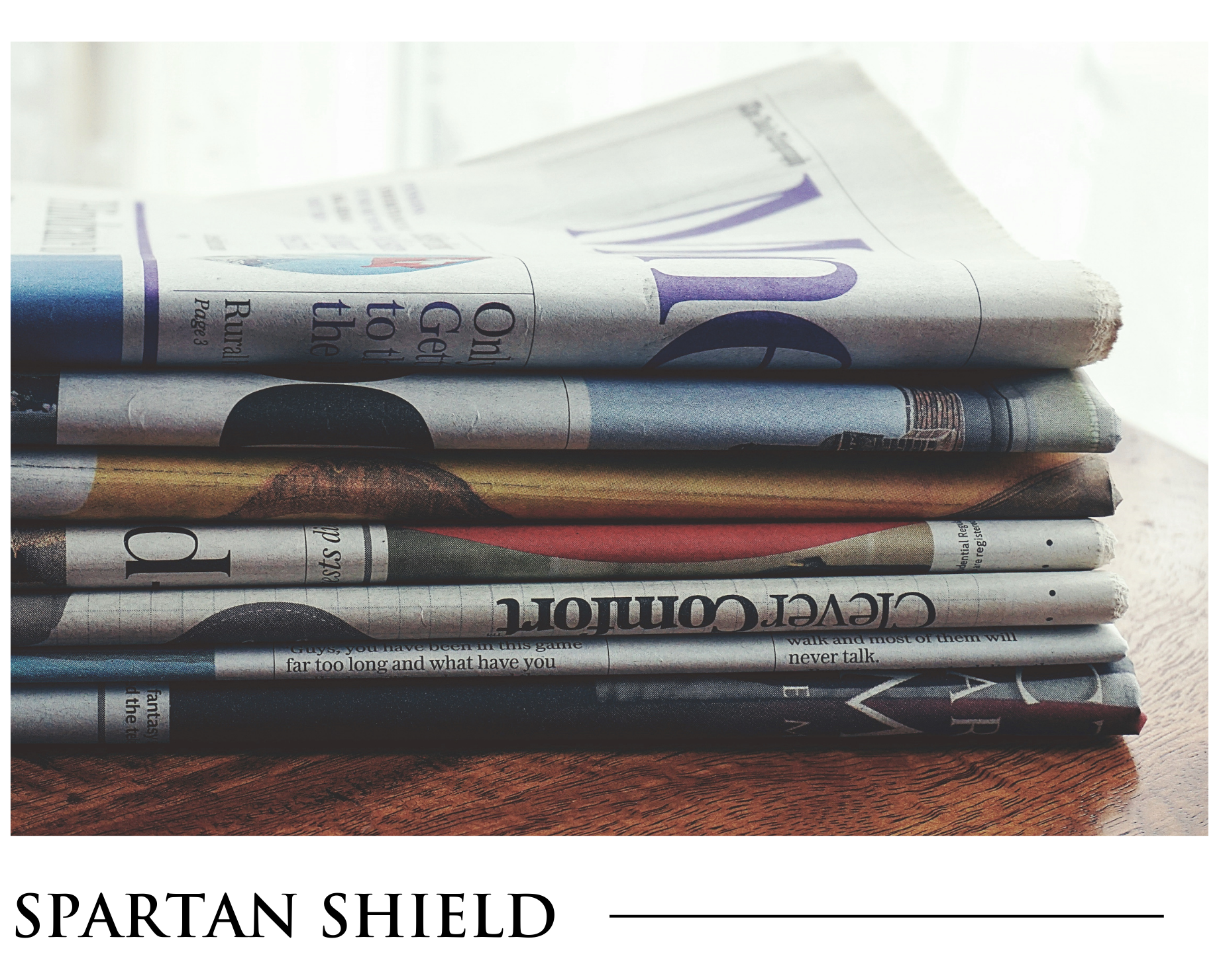 A stack of newspapers with the words spartan shield on the bottom