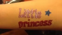 A glittery temporary tattoo on skin reading 
