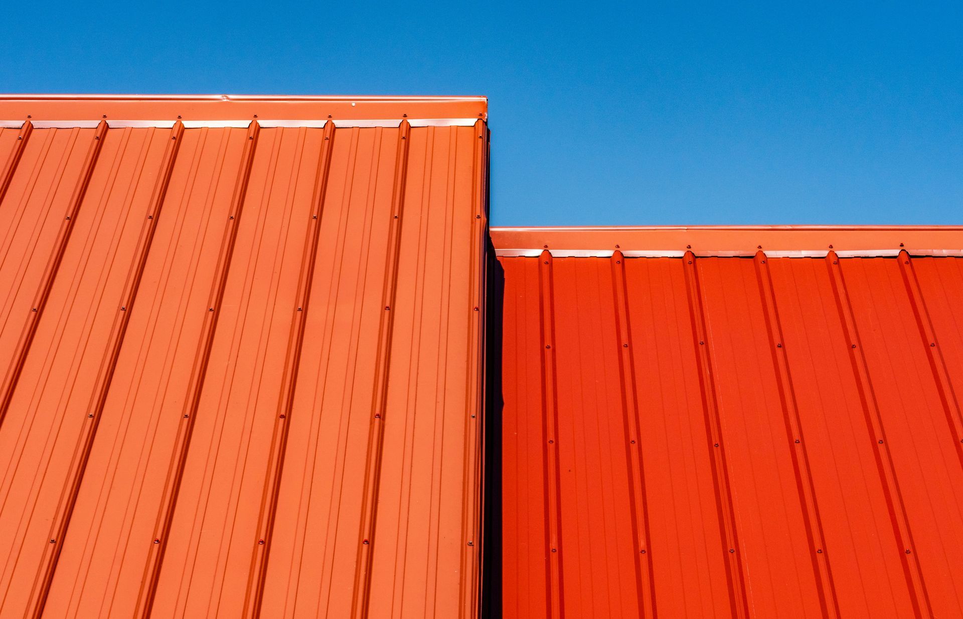 Two red roofs are against a blue sky.