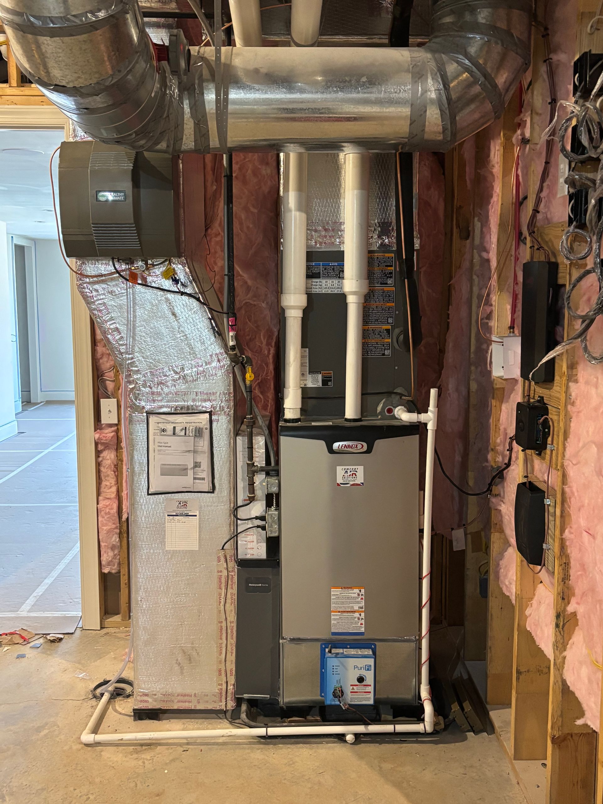 HVAC system installation in a partially built room: furnace, air handler, ducts, insulation.