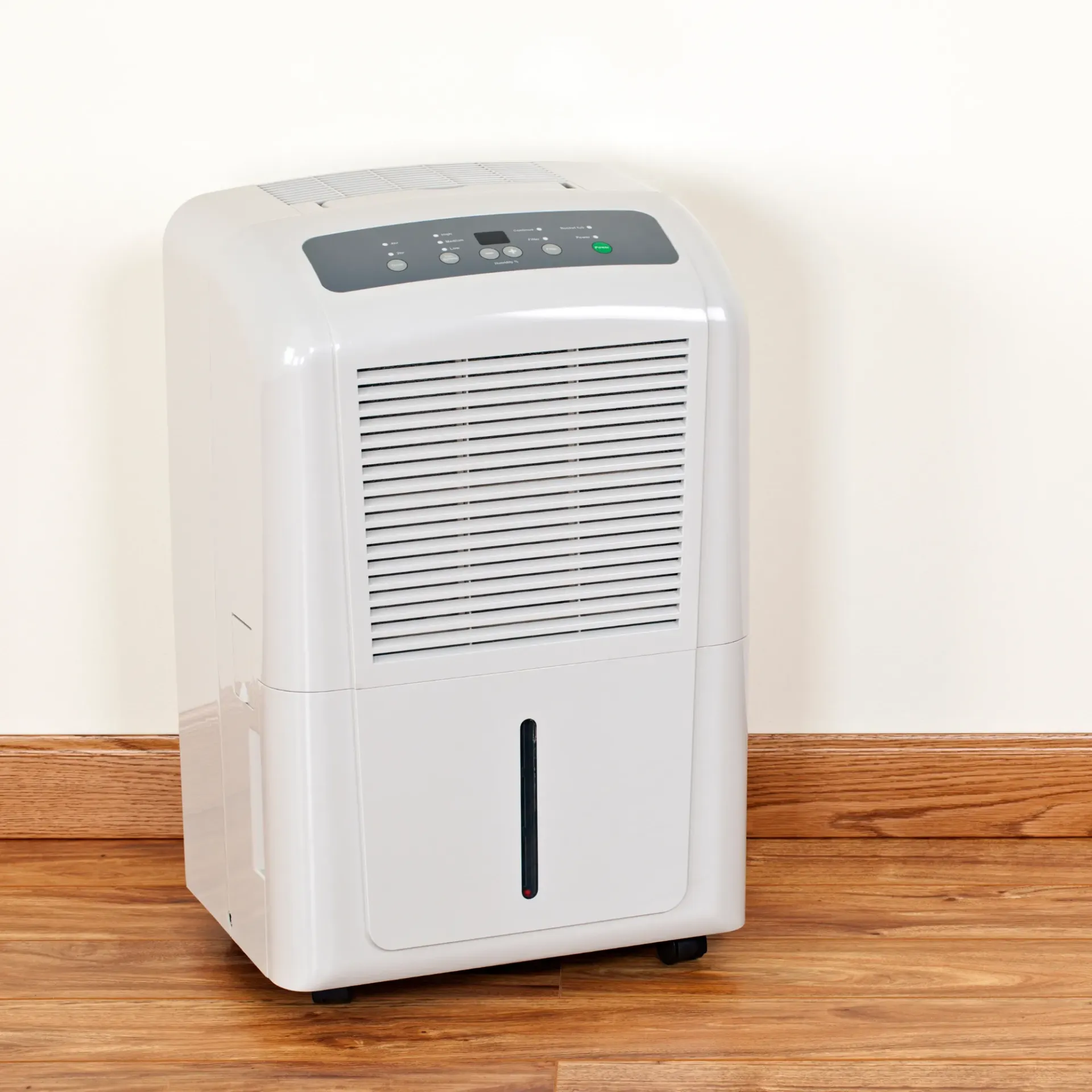 Comfort Air Solution LLC - A white dehumidifier is sitting on a wooden floor next to a wall.