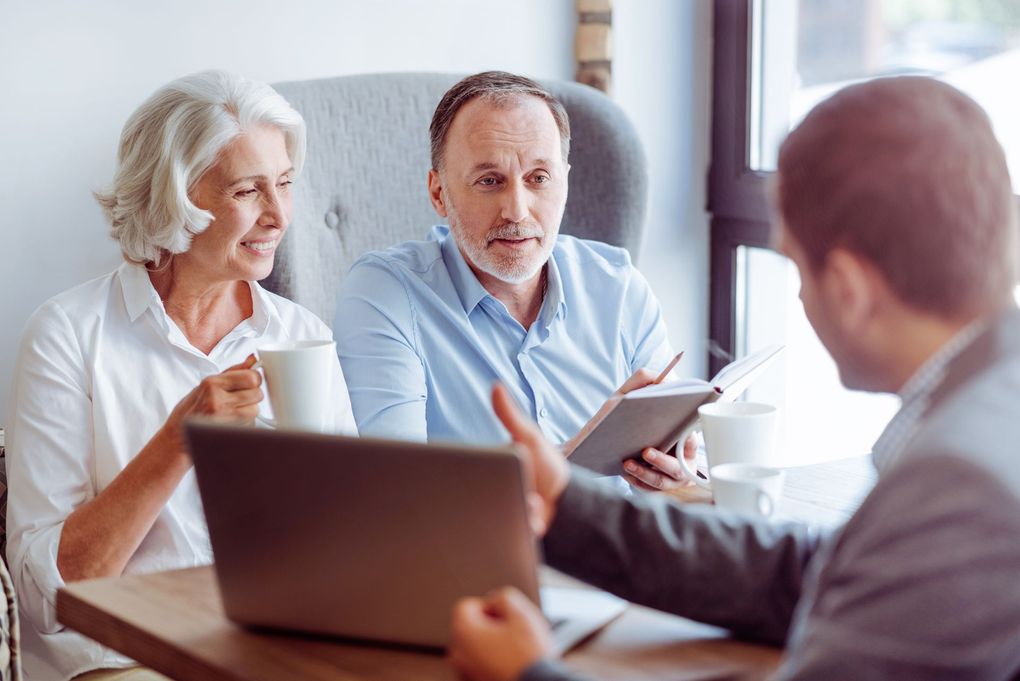 Three people in a meeting, one showing a tablet while others listen with a laptop open. Three people in a meeting, one showing a tablet while others listen with a laptop open.