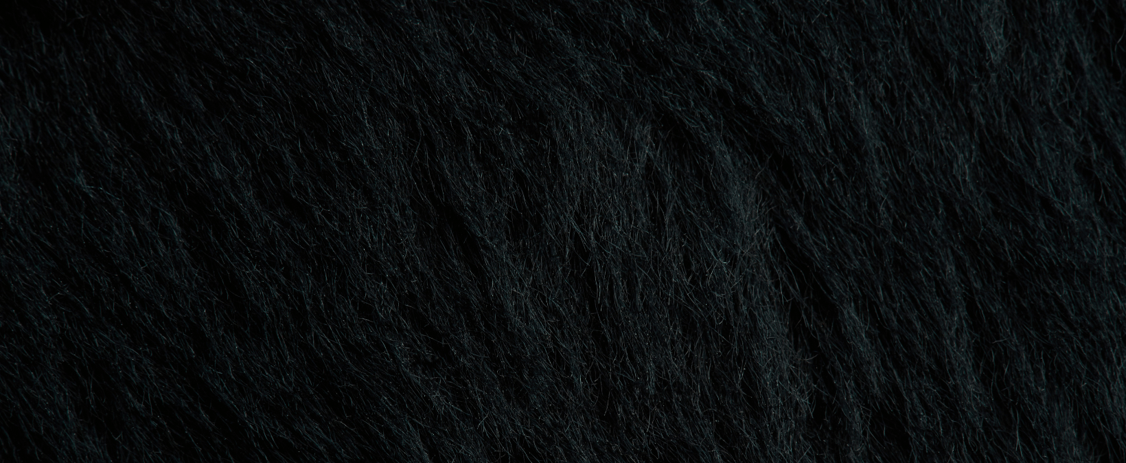 Close-up van een dicht, donker gestructureerd oppervlak met hier en daar glinsterende accenten.