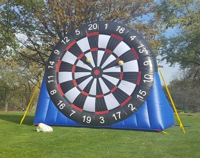 a large inflatable soccer dart board is sitting on top of a lush green field .