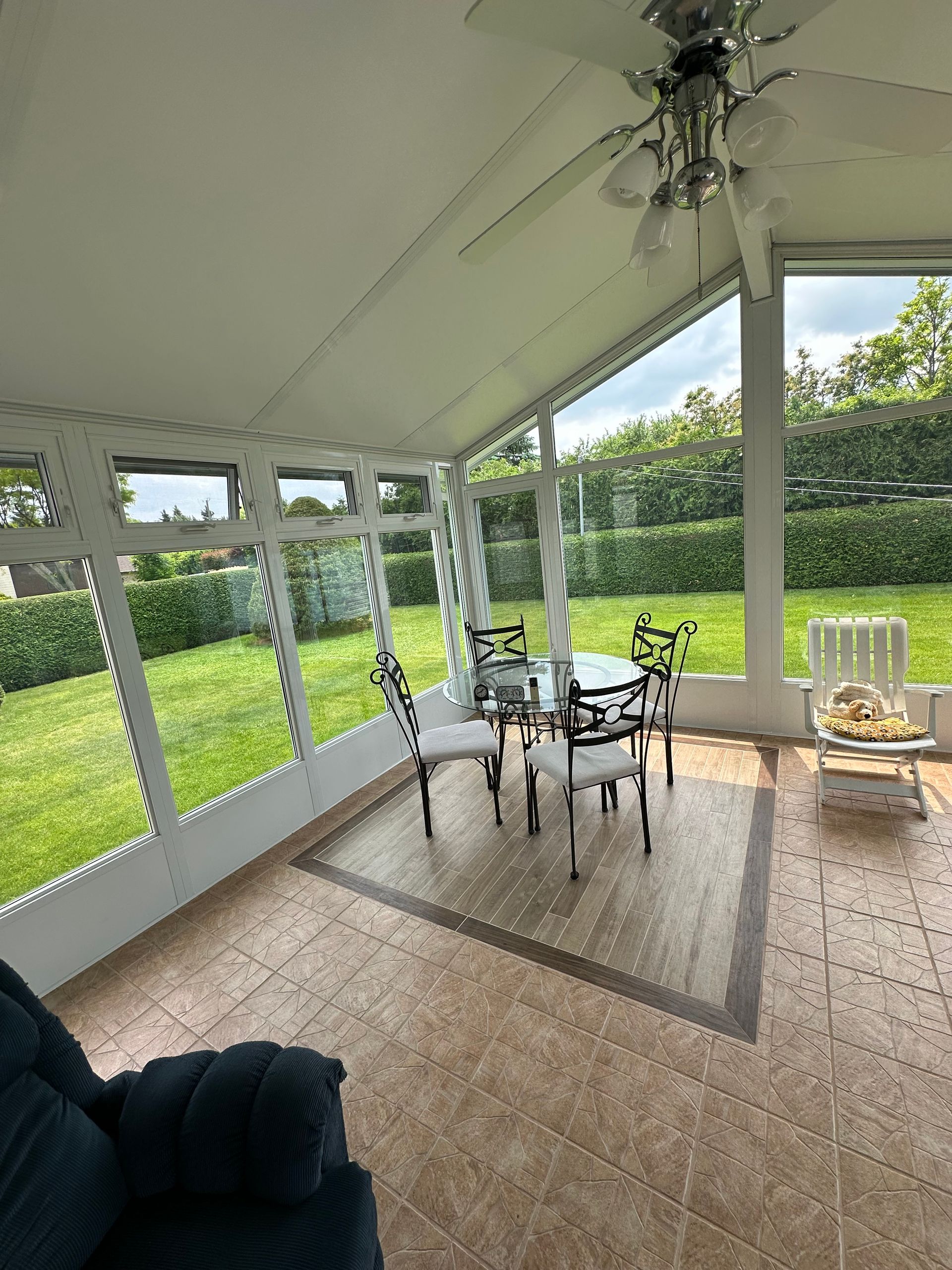 Véranda avec table et chaises, donnant sur une pelouse verdoyante.