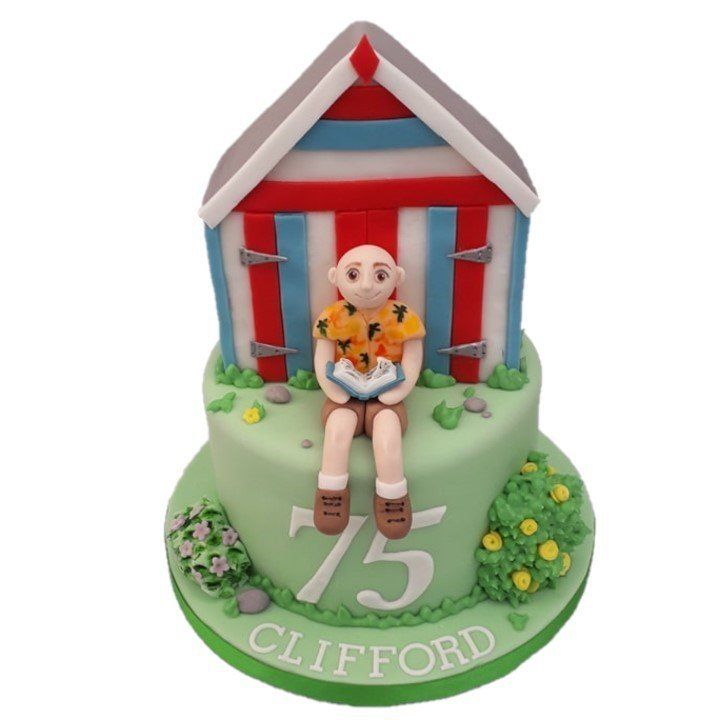 Man reading book and garden shed on top of garden cake. Created by A Cherry On Top