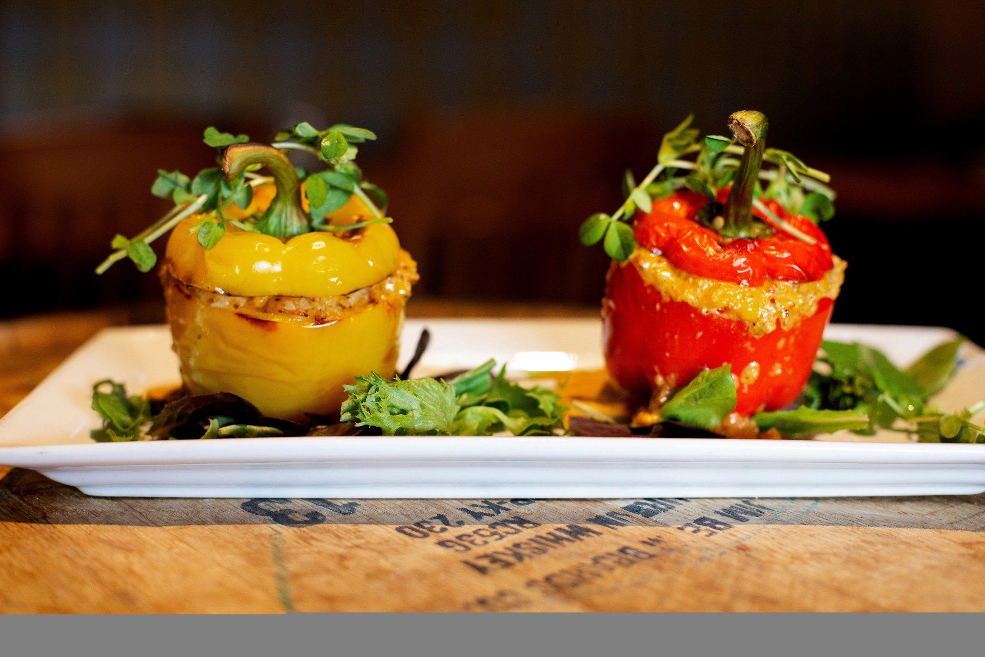 Yellow and red stuffed bell peppers with green garnish on a white plate.